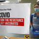 Deputy charge nurse Katie McIntosh stands in front of a sign that reads, "Join the resistance, get vaccinated."